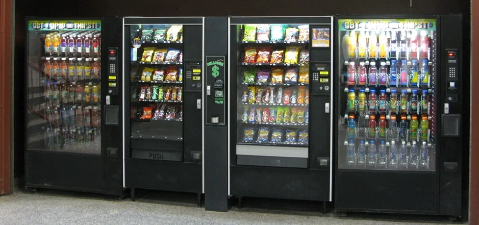 Four vending machines in an office lobby: two cold drink cabinets and two snack cabinets