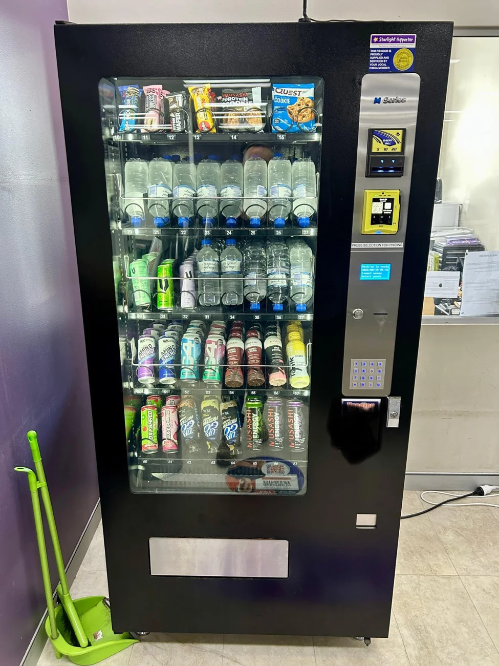 Stocked combination vending machine with snacks, bottled water, cans and a cashless card reader